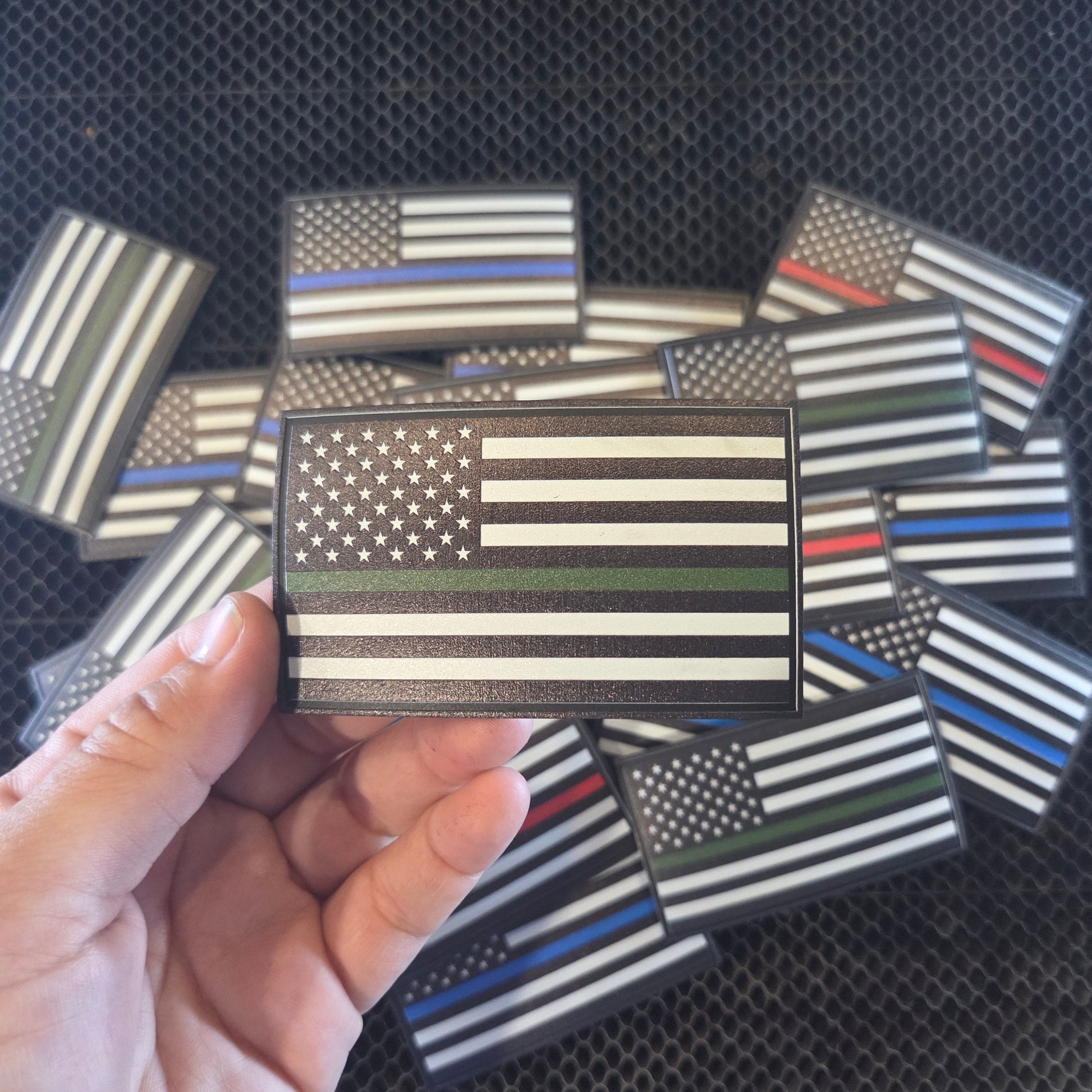 Hand holding a small American flag patch with others in the background on a textured surface