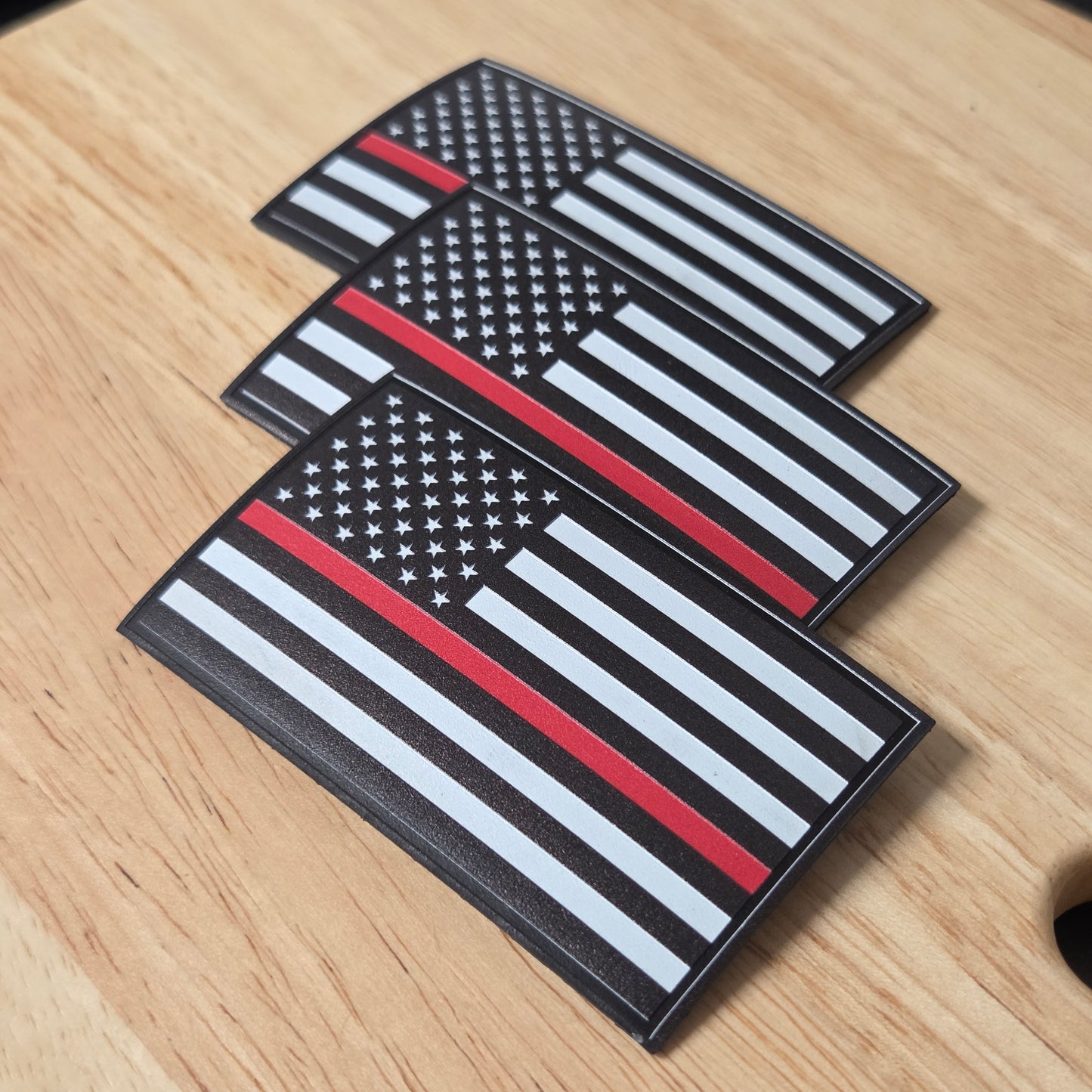 Three American flag patches with a thin red line on a wooden surface
