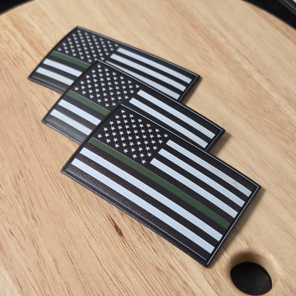 Three American flag patches with thin green line on a wooden surface