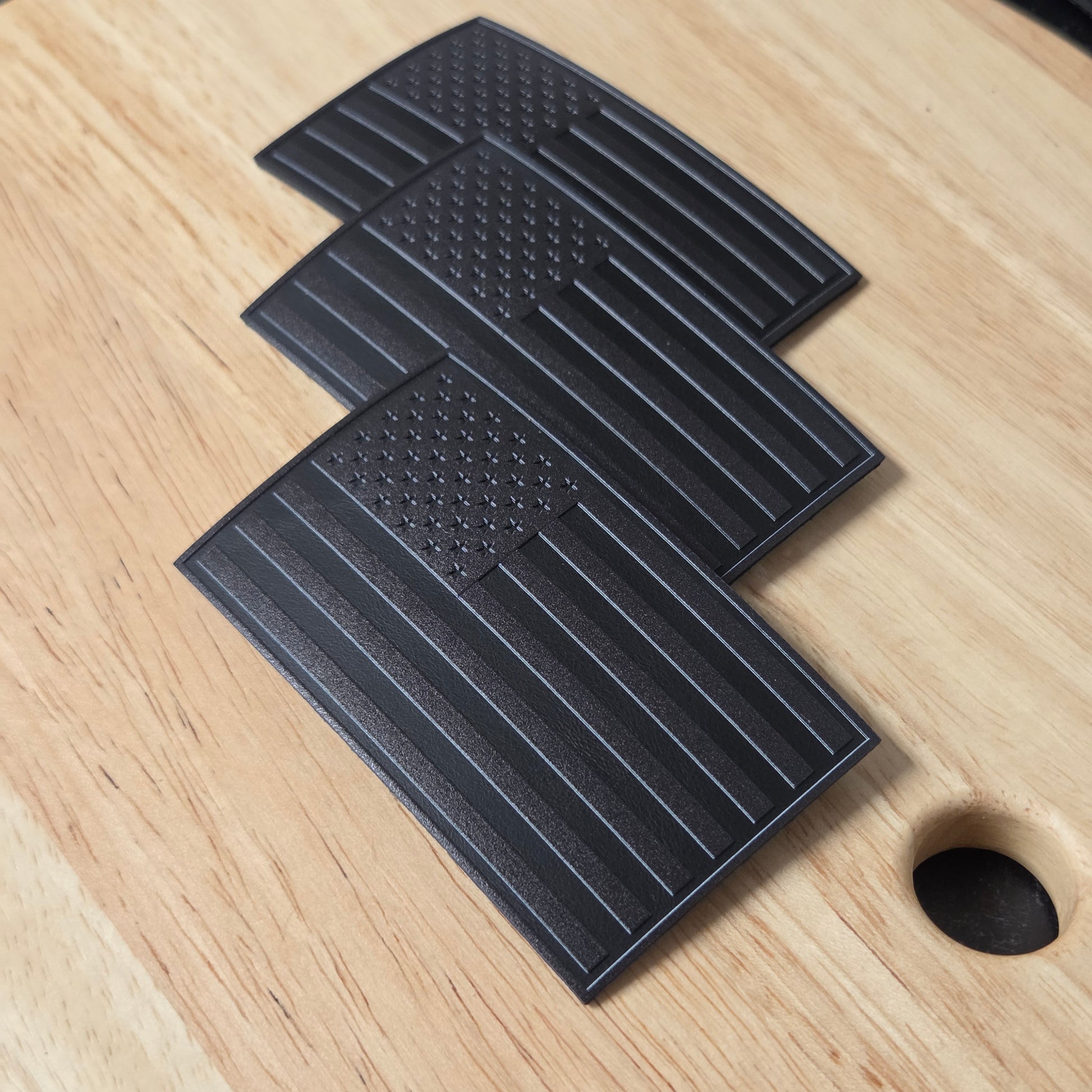 Three all black American Flags on a wooden surface