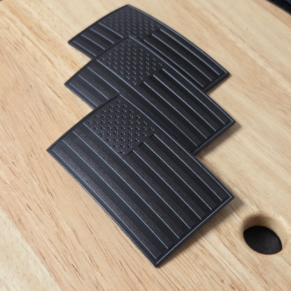 Three all black American Flags on a wooden surface